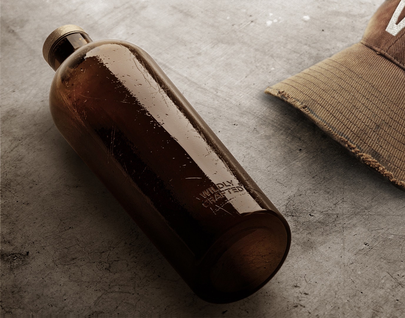 Estal Wild Gemaakt Sfeerbeeld: bruine fles van de Wildly Crafted-collectie ligt op een grijze betonnen achtergrond, ernaast een bruine pet